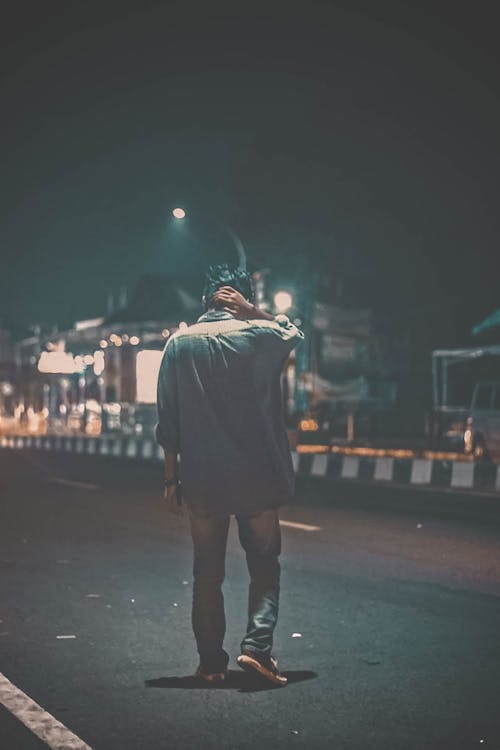 Man Walking Down a Road at Night