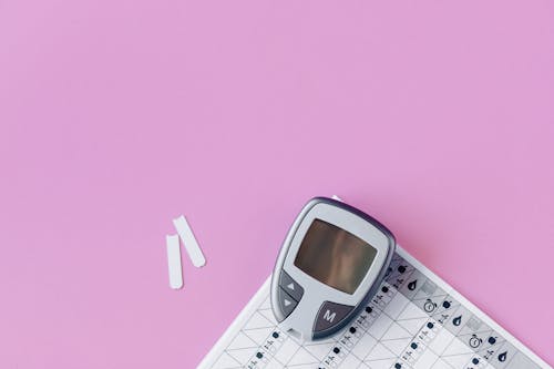 A Blood Glucose Monitoring Equipment over a Pink Surface