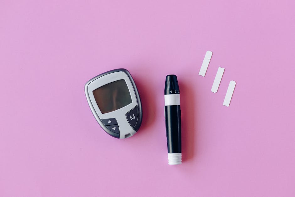 Flat lay of diabetes testing kit with glucometer and lancet on pink surface.