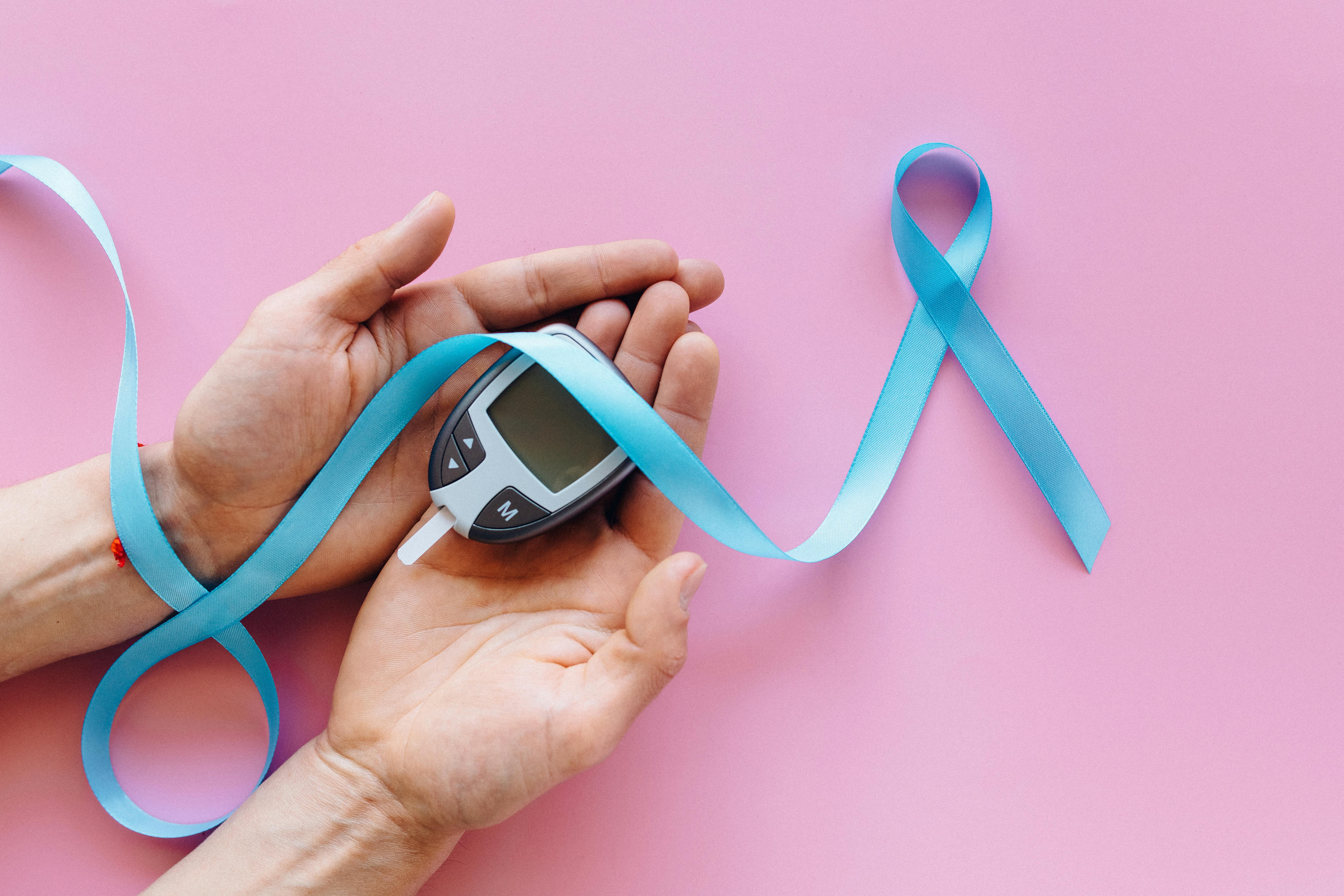 blue ribbon and glucometer on person s hands