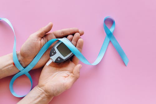 Blue Ribbon and Glucometer on Person's Hands