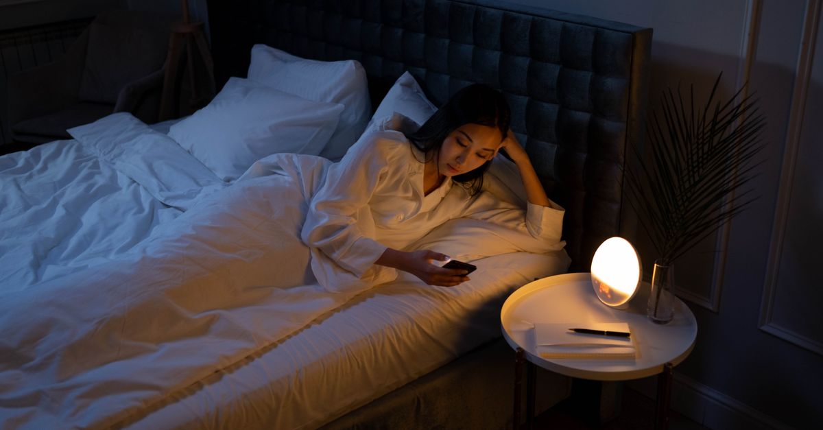 A person sleeping deeply in a dark, peaceful bedroom with no phone in sight