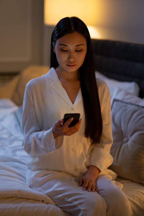 Free A Woman in Her Pajama Looking at Her Cellphone Stock Photo