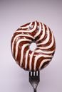 Delicious chocolate donut on fork in gray studio