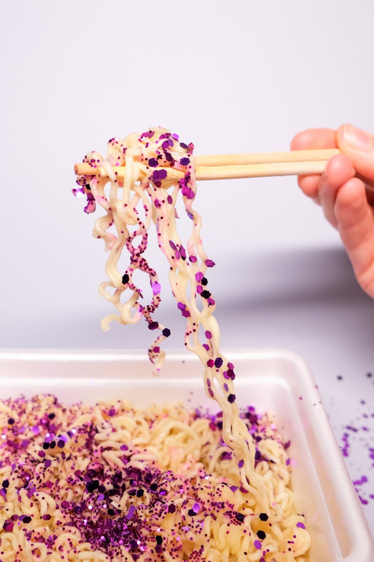 Faceless Person Using Chopsticks While Eating Bowl Of Noodles