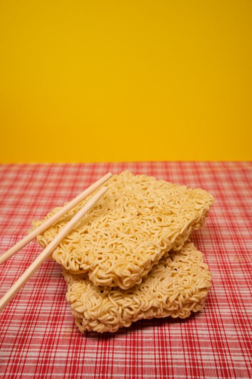 Free From above of bamboo chopsticks placed on dried uncooked instant noodles in block form on table in kitchen Stock Photo