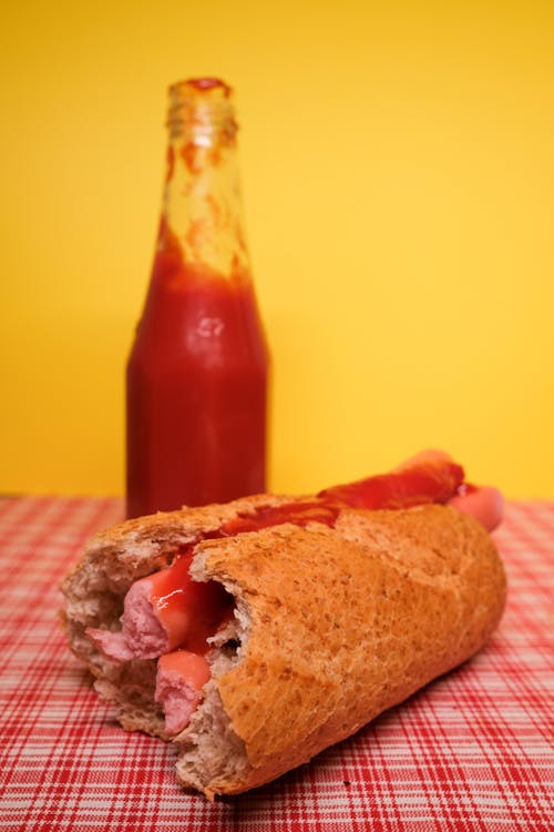Homemade hot dog and bottle of ketchup placed on table