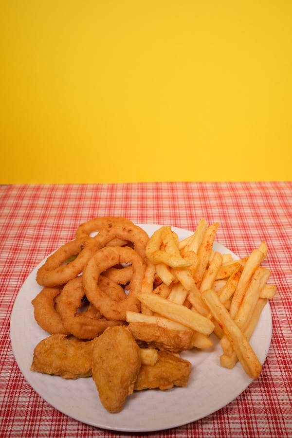 Plate with French fries and onion rings with nuggets