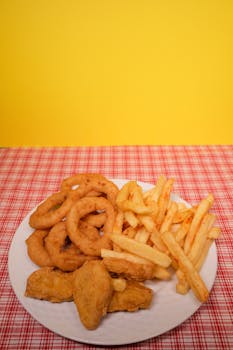 Crispy onion rings, French fries, and nuggets served on a vibrant red plaid tablecloth.