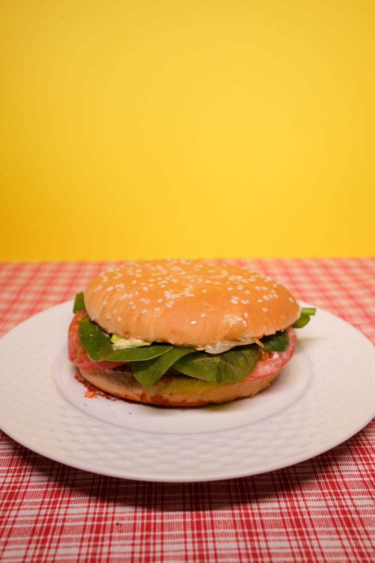 Burger With Salad Leaves And Tomatoes On Plate On Table