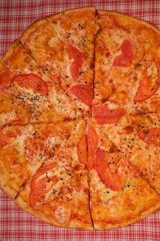 Top view of slices of pizza with tomatoes and cheese with seasoning on table