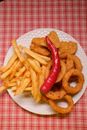 French fries and onion rings with nuggets and chili pepper