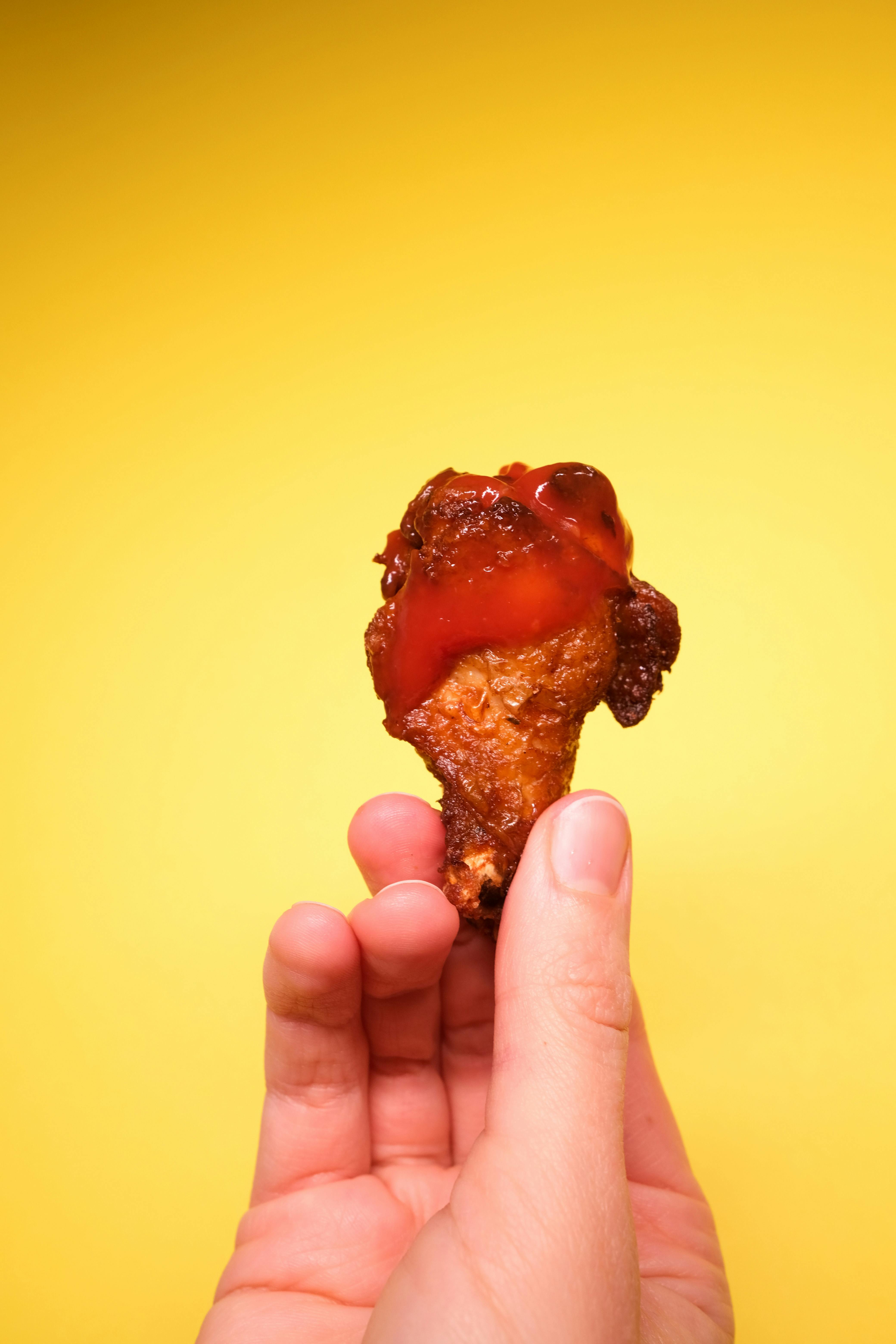 anonymous person demonstrating fried chicken with ketchup in hand