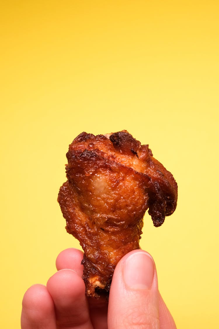 Unrecognizable Person With Fried Chicken In Fingers