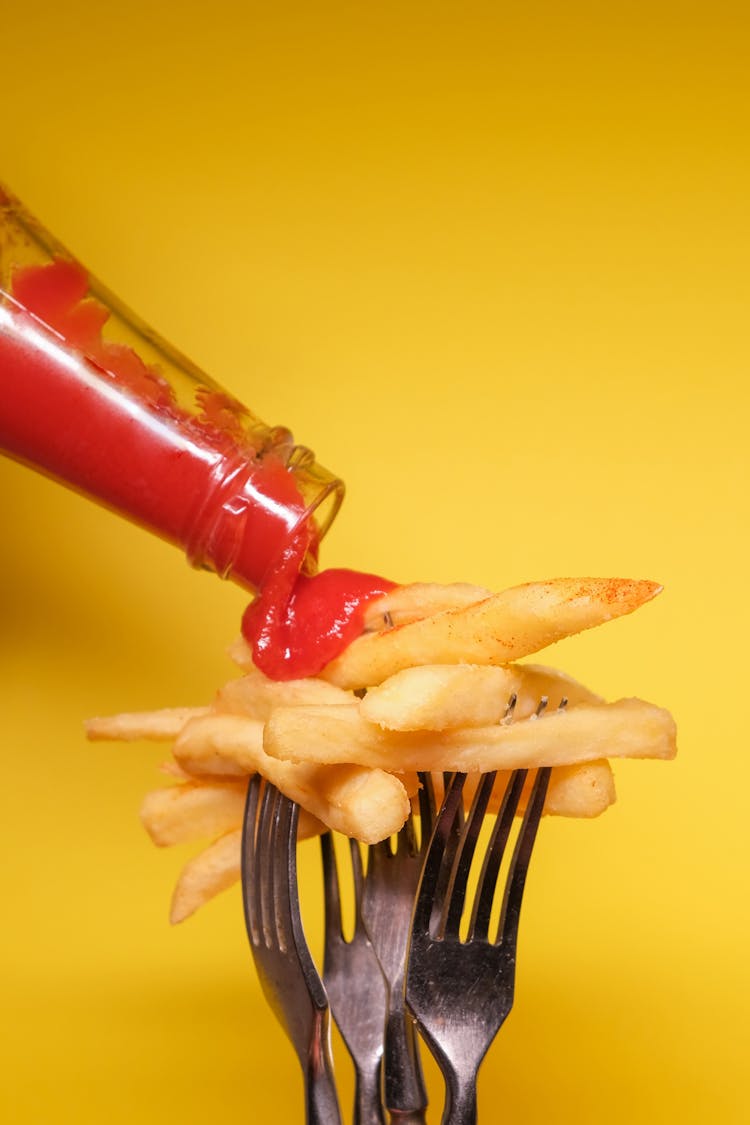 French Fries On Forks With Ketchup Near Yellow Wall