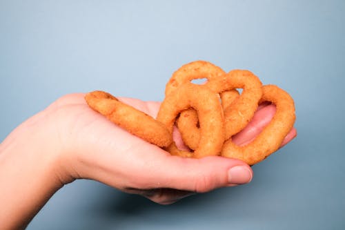 Free Faceless person with deep fried onion rings in hand Stock Photo