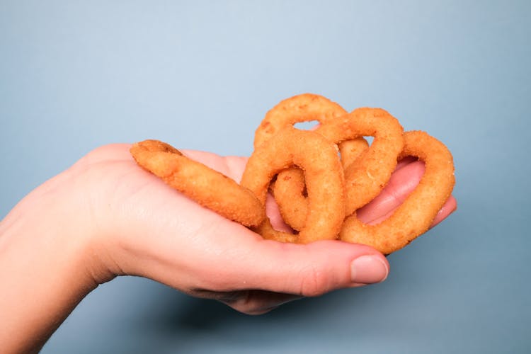 Faceless Person With Deep Fried Onion Rings In Hand