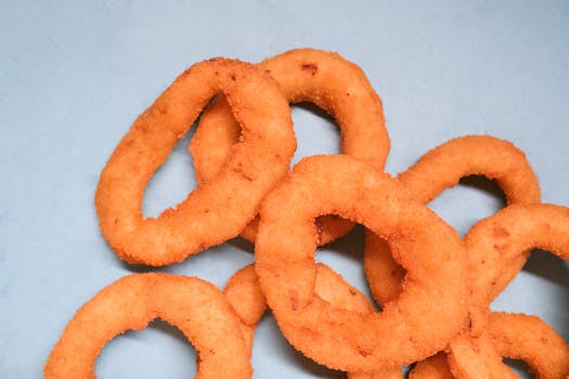 Crispy golden onion rings on a vibrant blue background, perfect for fast food visuals.
