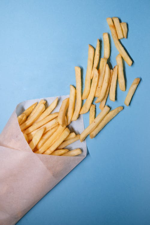 Fried potatoes in paper on blue background