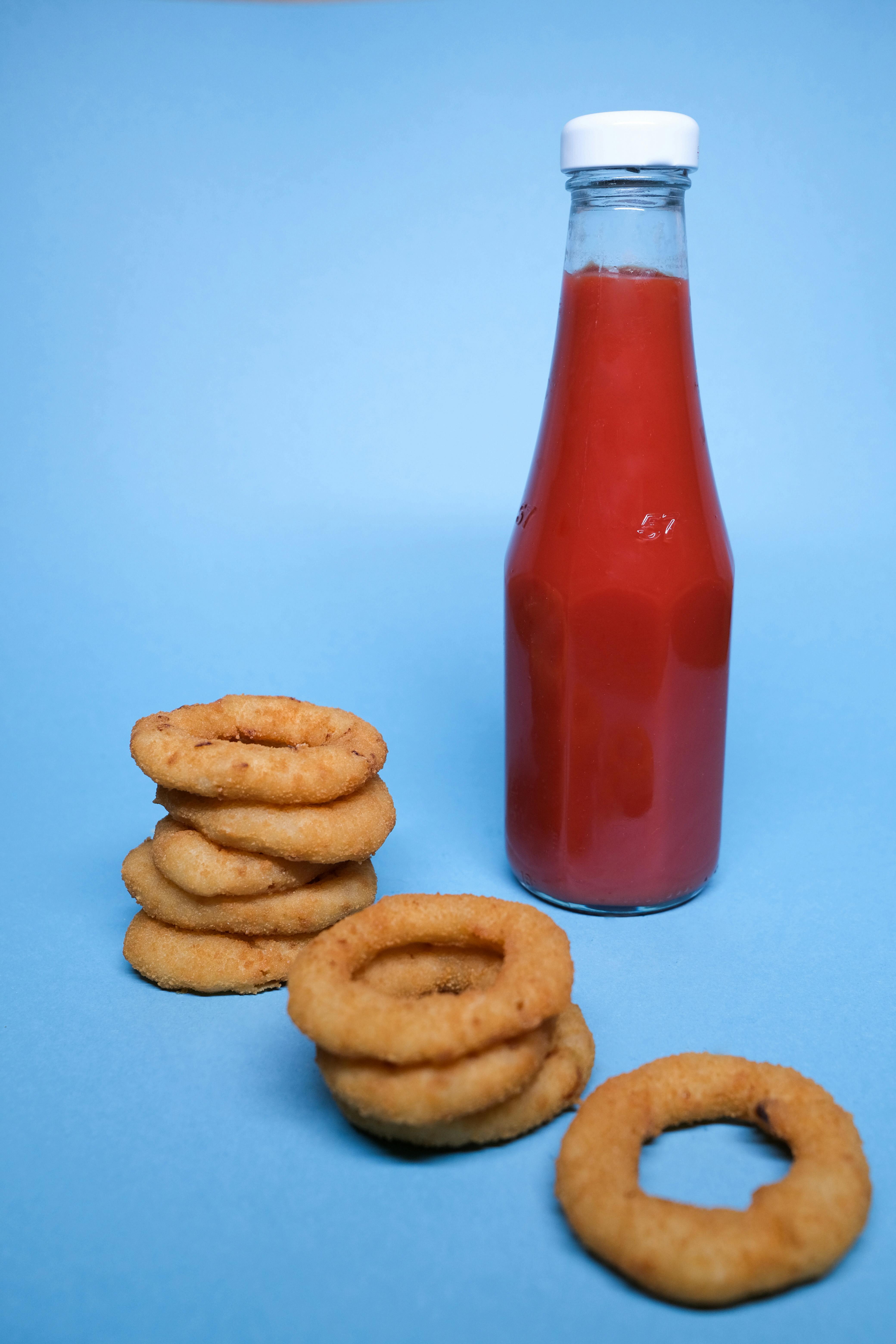 onion rings near ketchup bottle on blue background