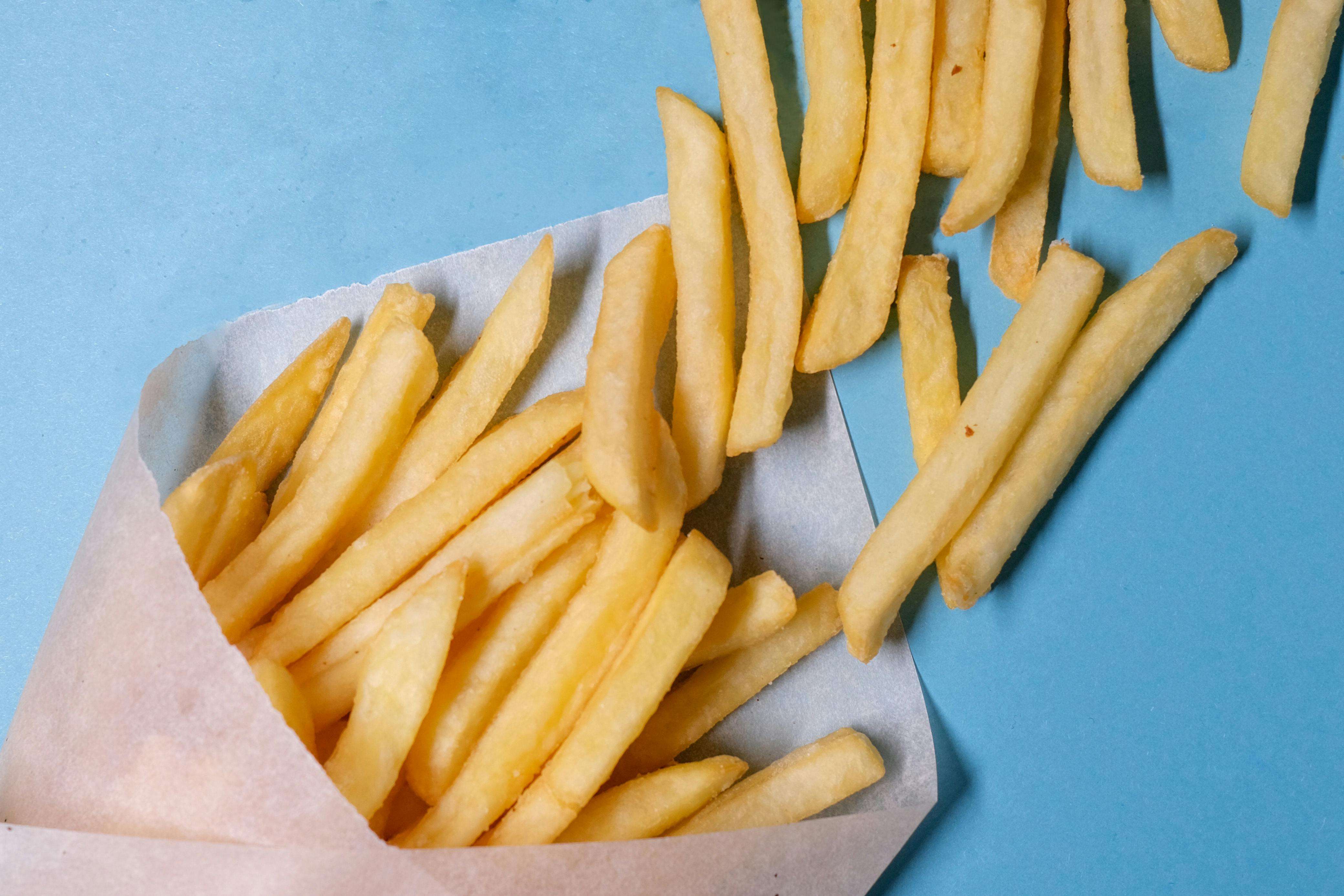 fried potatoes in paper on blue background