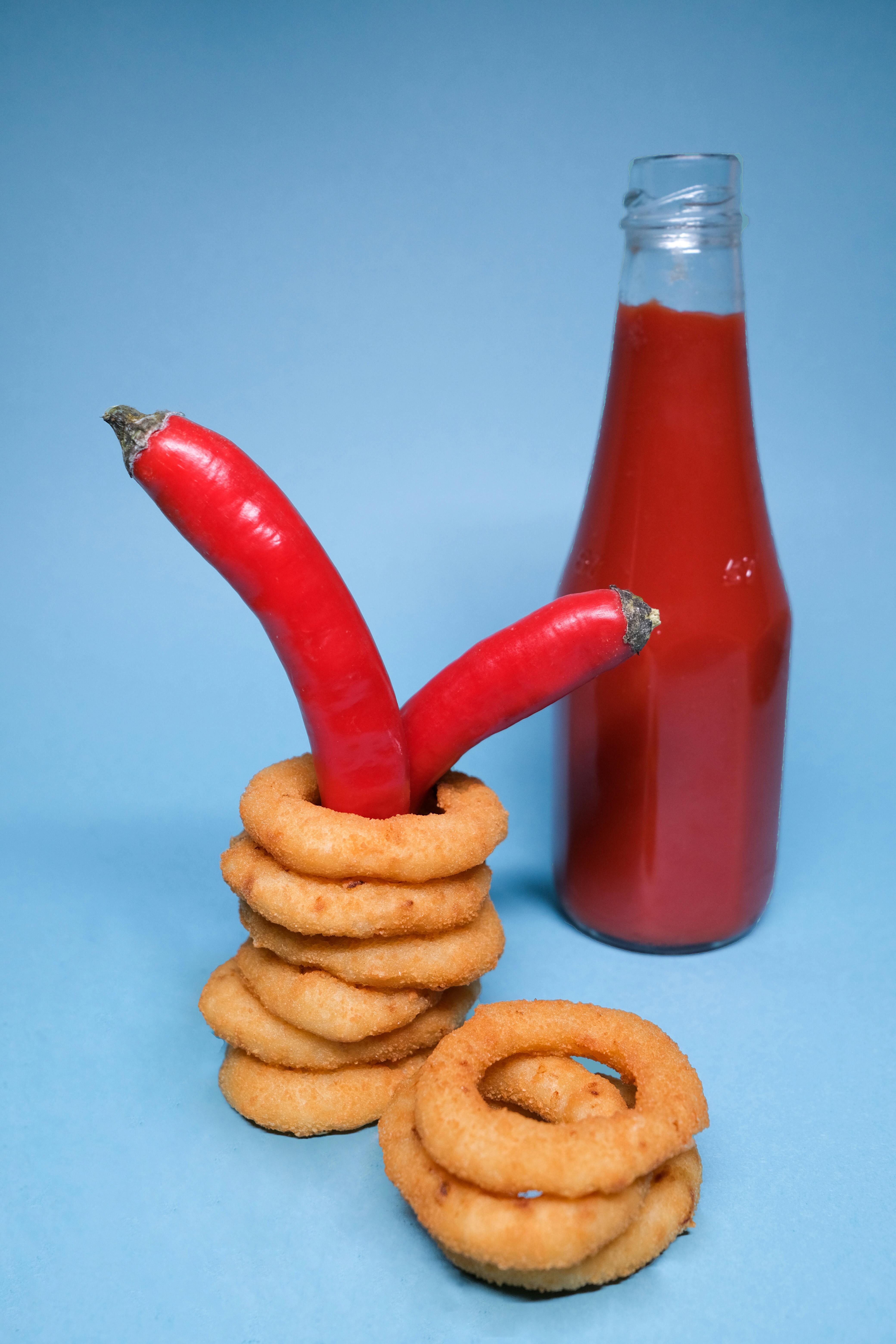 onion rings and ketchup with chili peppers on blue surface