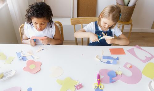Free Two children crafting colorful paper shapes, focusing on creativity and fun in an indoor setting. Stock Photo