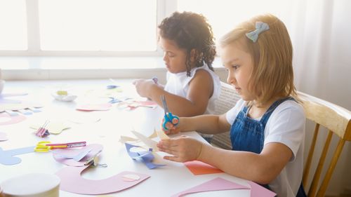 Free Young children enjoying a fun and educational paper craft activity indoors. Stock Photo