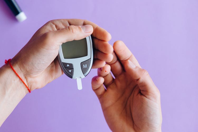 Person Holding A Glucose Meter 