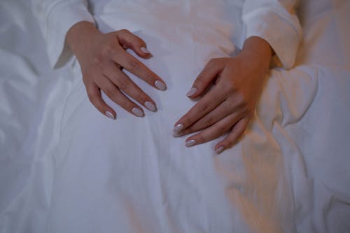 A Person's Hands over White Textile