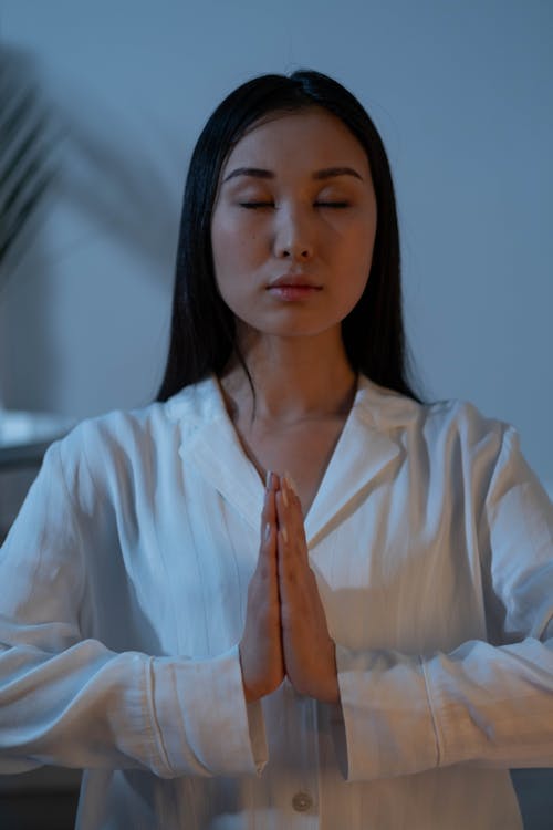 A Woman in White Long Sleeves Meditating