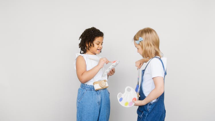 Two Kids Holding A Paintbrush And A Palette