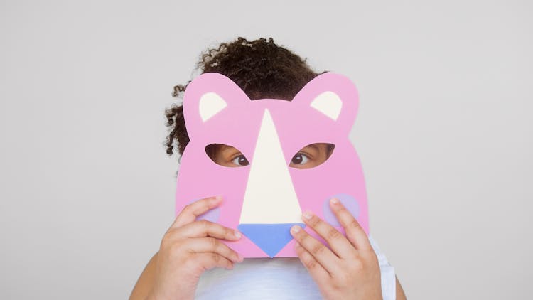 Girl Covering Her Face With A Cutout Animal Mask