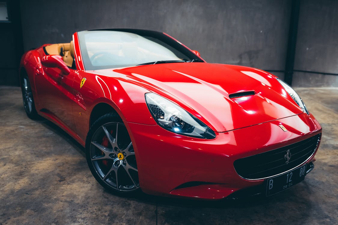 Free Expensive glossy red convertible with polished body parked in garage with concrete wall Stock Photo