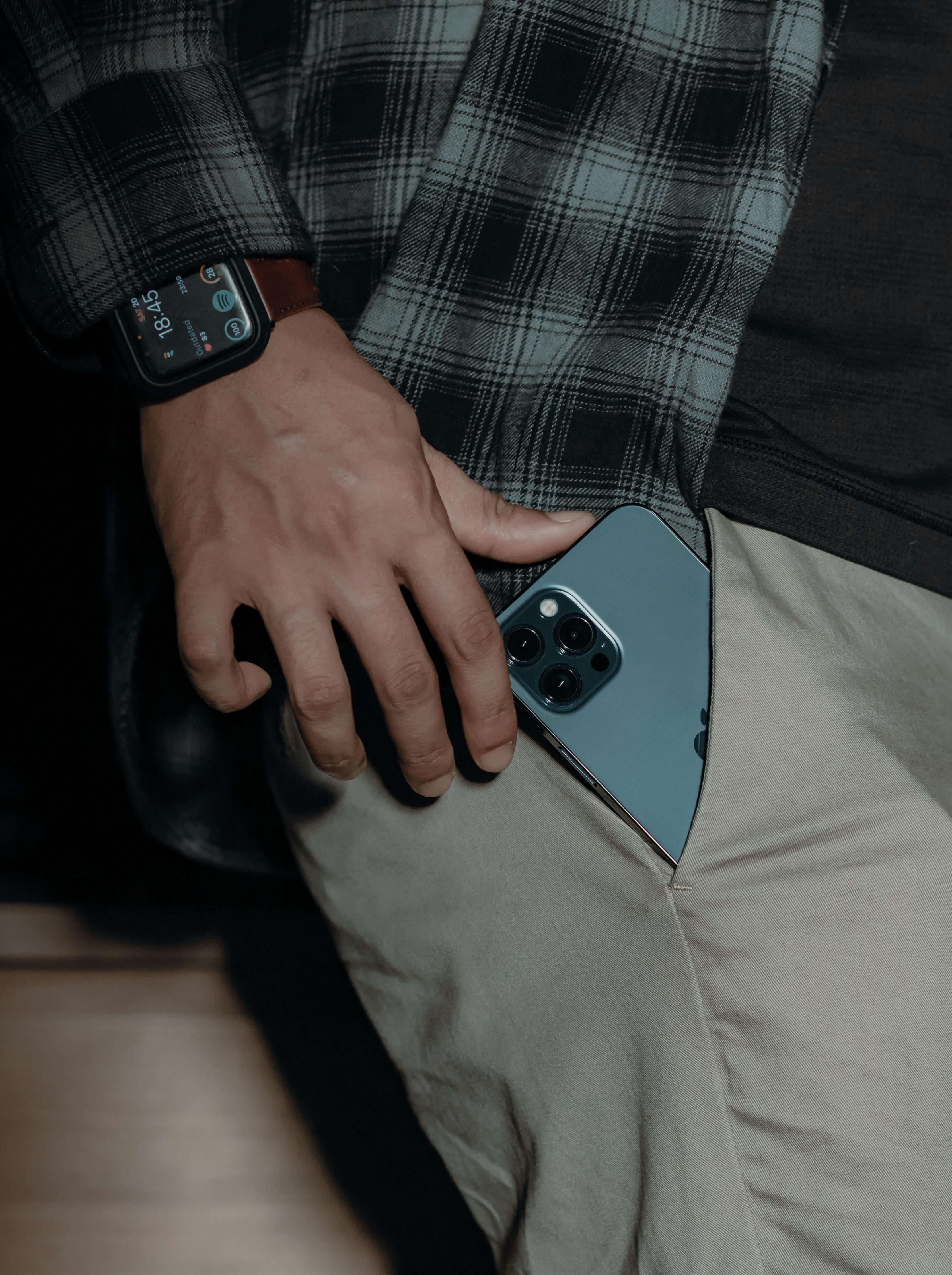 man putting smartphone in pocket of pants