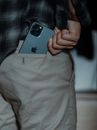 Crop anonymous male in casual clothes putting expensive smartphone in pocket of pants
