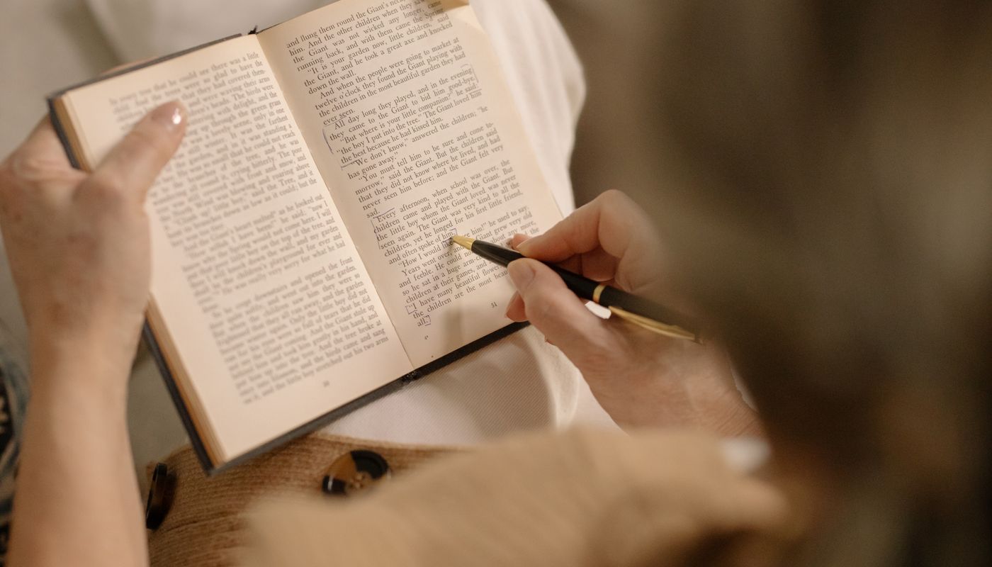 A person reading a book in warm indoor light, turning a page slowly