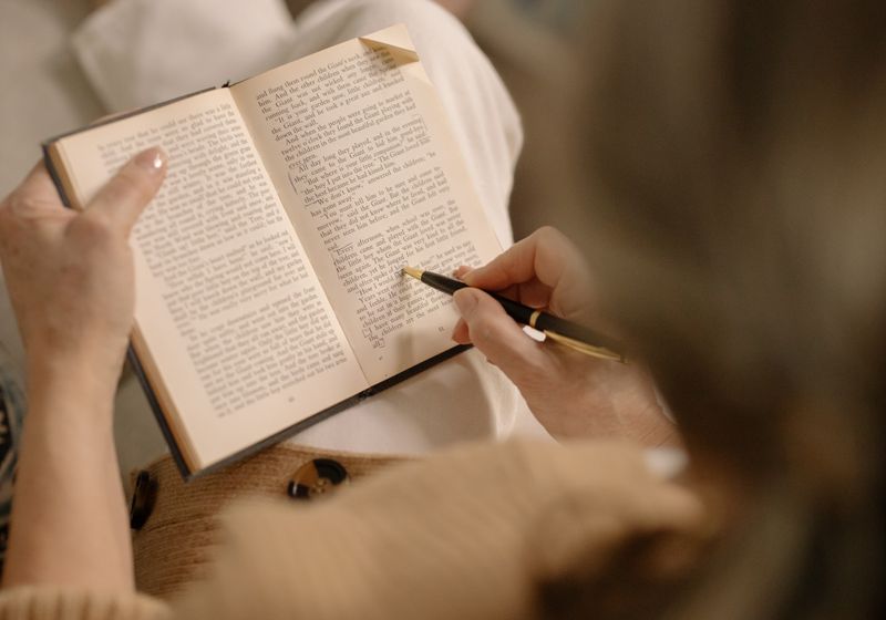 A person reading a book in warm indoor light, turning a page slowly