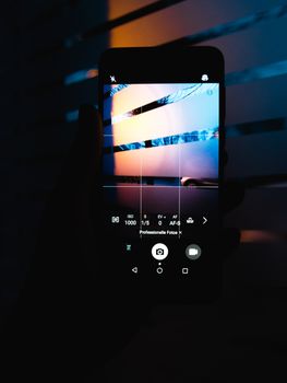 Silhouetted smartphone capturing an artistic scene through its camera screen.