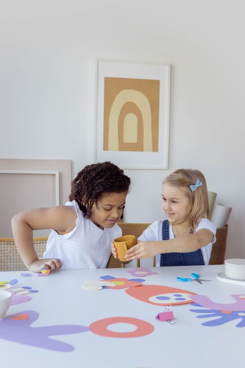 Free Two girls engaging in arts and crafts, sharing creative moments at a table indoors. Stock Photo