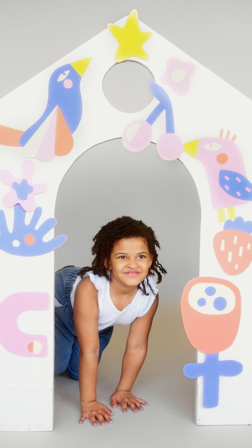 Free A cheerful child crawling through a handmade colorful playhouse, expressing creativity and joy. Stock Photo