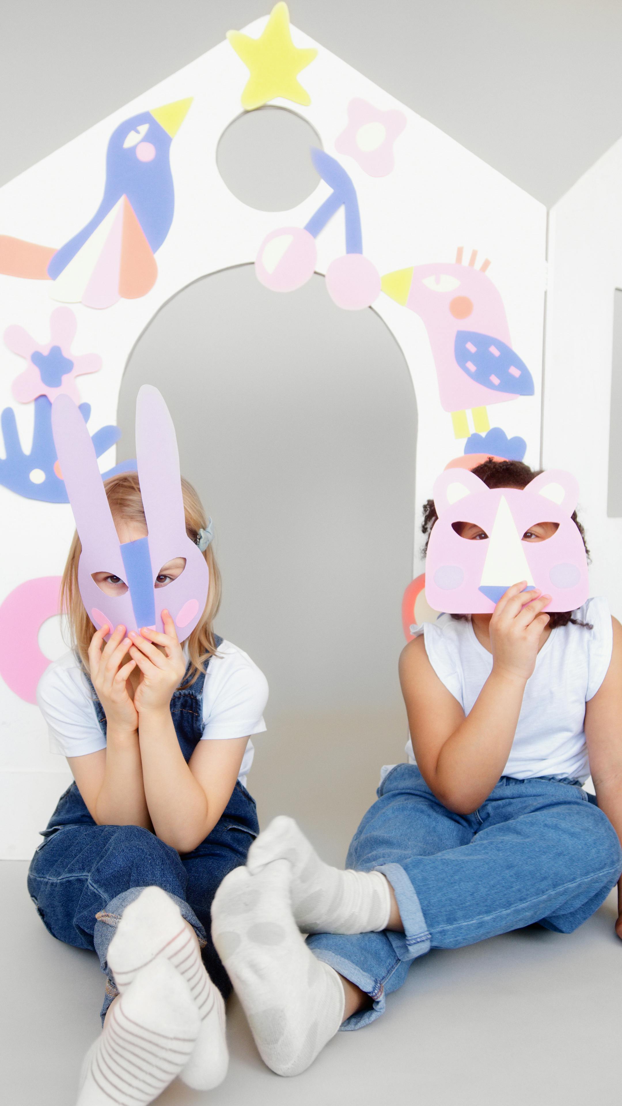 two kids covering their faces with a cutout animal mask