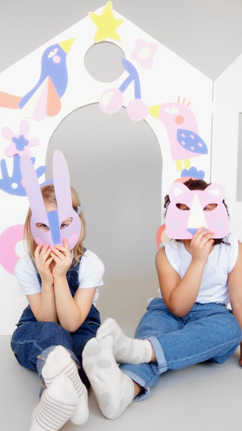 Two Kids Covering Their Faces With a Cutout Animal Mask