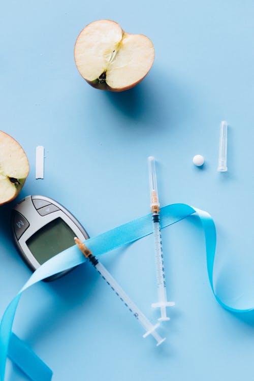 Blood Sugar Meter and Syringe on a Blue Background