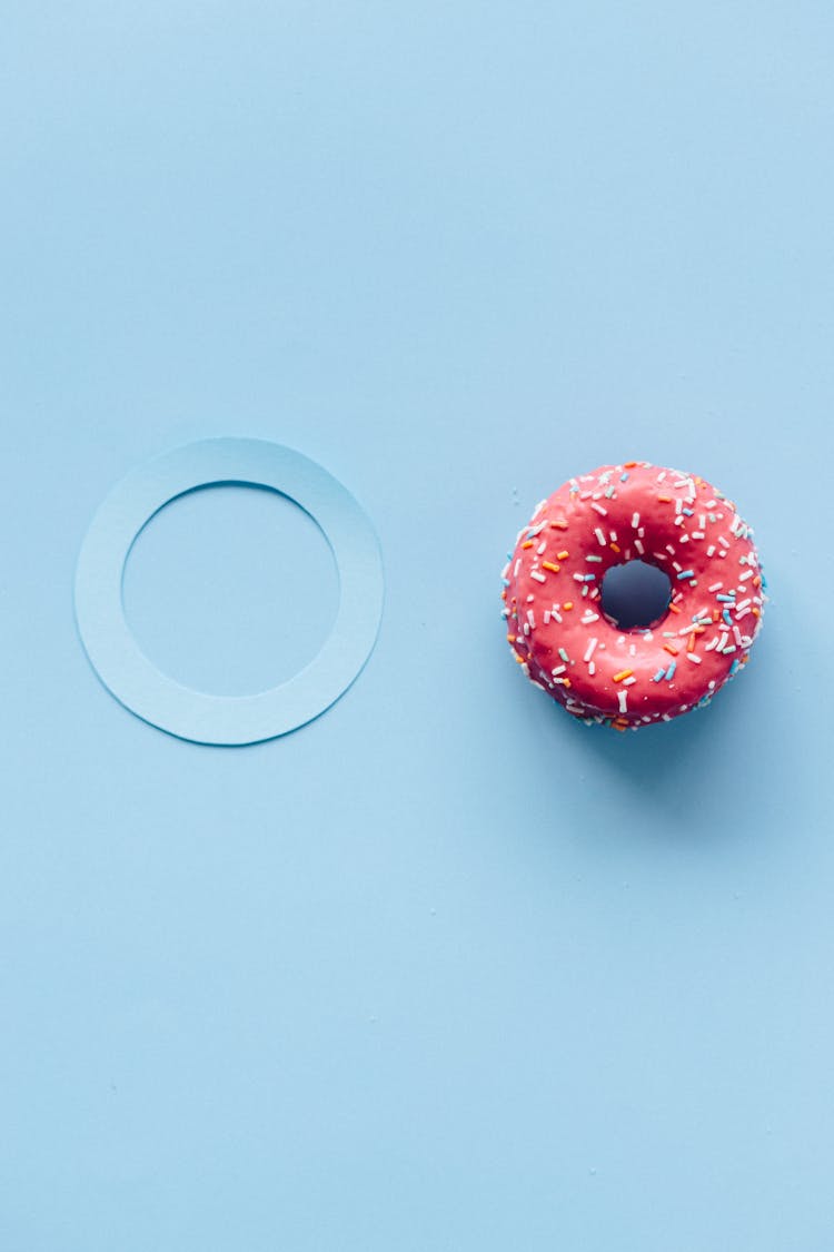 Pink Donut With Sprinkles On Blue Surface