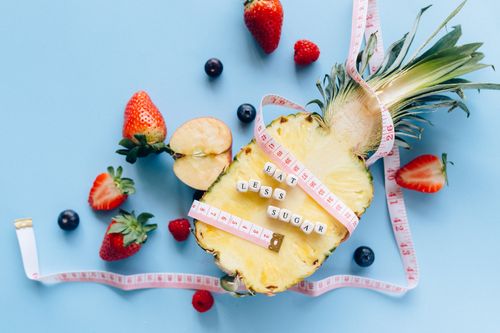 Free A sliced pineapple with berries and a tape measure on a blue background promoting healthy eating. Stock Photo