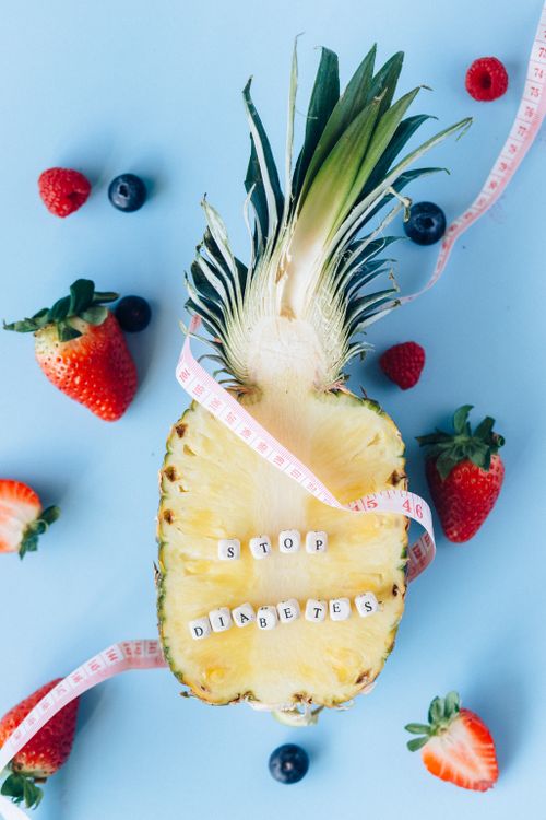 Free Creative diabetes awareness concept with pineapple, berries, and measuring tape on a blue background. Stock Photo