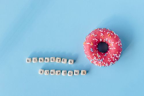 Free A pink frosted donut with diabetes symptoms text on a blue background, highlighting awareness. Stock Photo