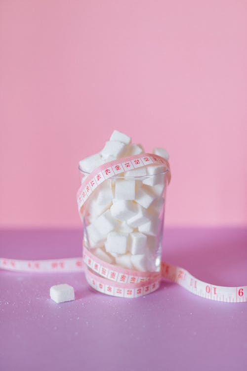 Blocks of Sugar on a Glass Surrounded by b Tape Measure