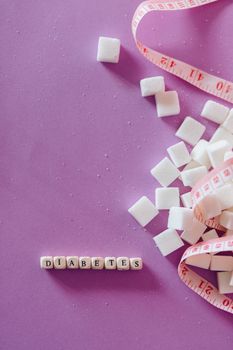 Sugar Cubes Beside Tape Measure Near Dices with Letter on a Pink Surface